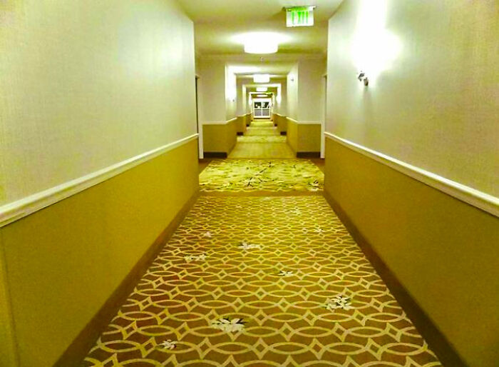 A long, deserted hotel hallway with patterned carpet, appearing as a haunting liminal space.