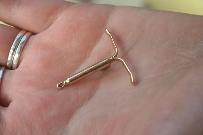 An IUD in a person's hand, representing a type of physical pain.