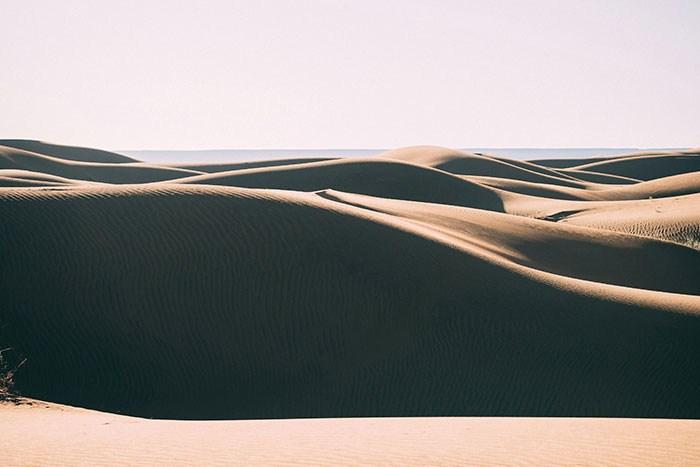 Sunlit sand dunes creating haunting shadows in desert terrain