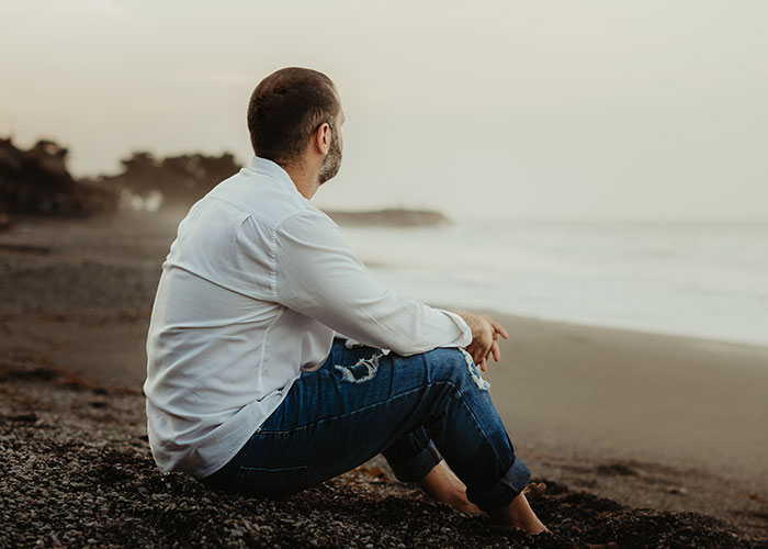 Man sitting alone on beach contemplating life choices