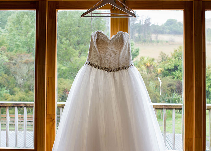 Wedding dress hanging by window with scenic outdoor view