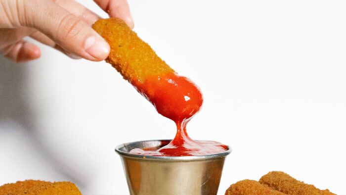 Hand dipping mozzarella stick in ketchup, mind-bending dilemmas food choice
