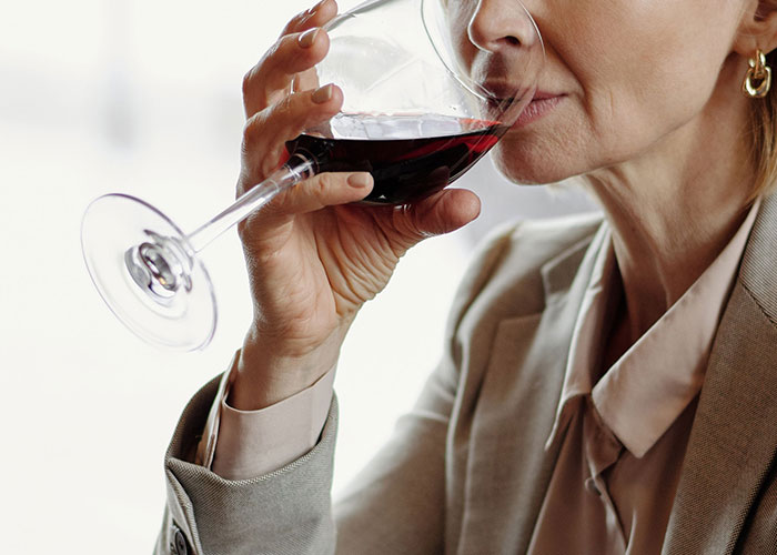 Woman sipping red wine, perhaps dealing with the emotional moments when kids lose contact with parents.