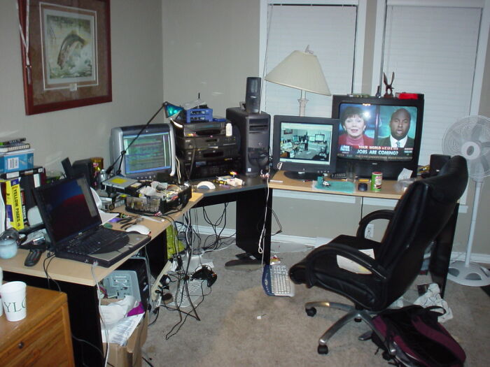 Cluttered computer setup with multiple monitors and equipment in a home office