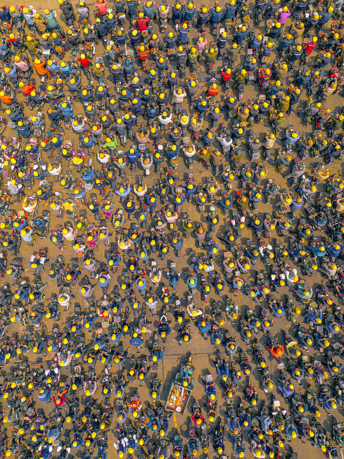 An aerial view of a large crowd of people, many holding yellow objects, a captivating Chromatic Awards photo.