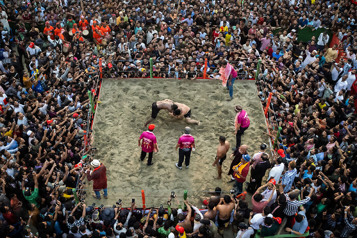 Two wrestlers in a sand ring surrounded by a large cheering crowd, an action photo from the 2025 Chromatic Awards.