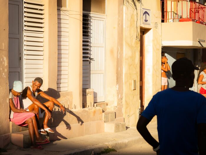 A photo of people sitting on doorsteps in a vibrant street, from the 2025 Chromatic Awards, telling stories.
