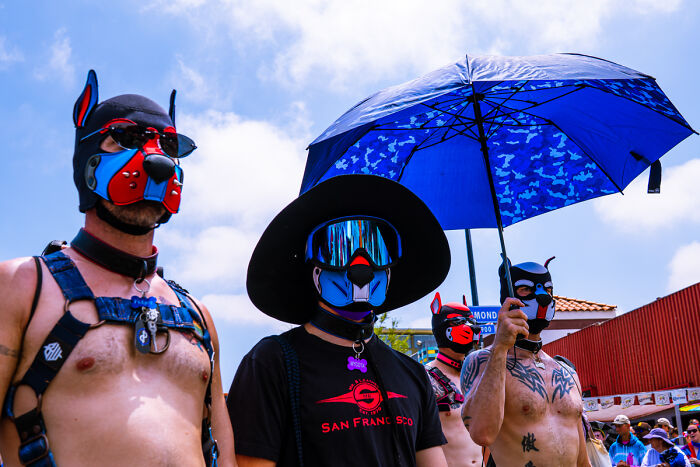 People in elaborate masks and harnesses under a blue umbrella at a Chromatic Awards event.