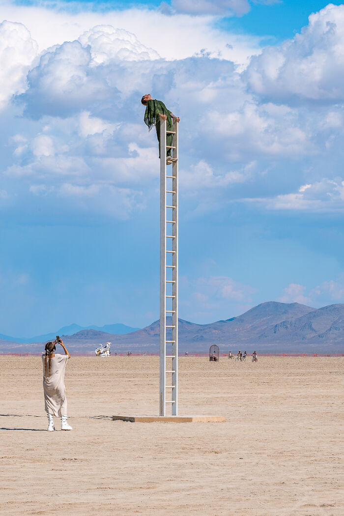 A person high on a ladder in a desert, symbolizing diverse stories of people captured for the 2025 Chromatic Awards.