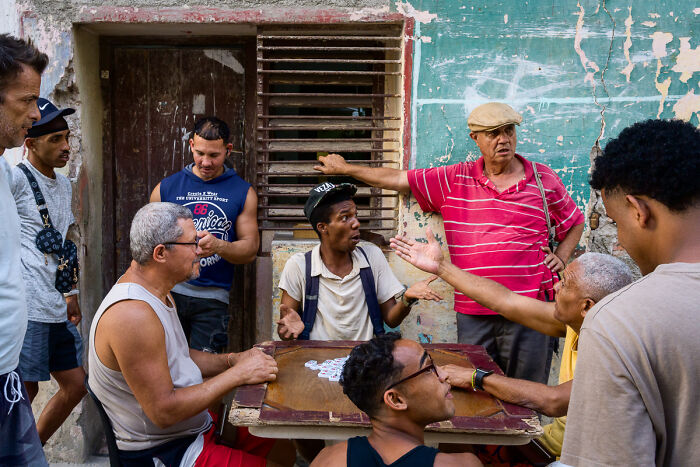 Men playing dominoes on a street, an engaging photo from the Chromatic Awards telling stories of people.