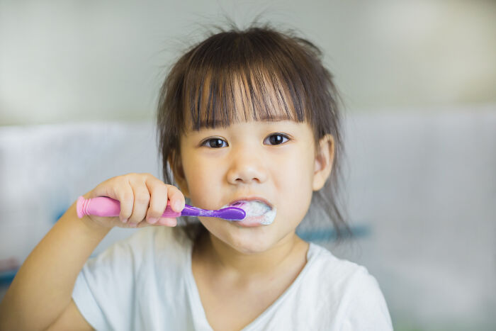 A young girl brushes her teeth, a daily interaction, not a plane interaction.