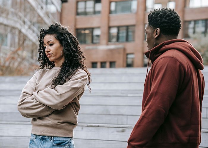 A couple arguing, one with crossed arms and a sad expression, conveying that family isn't everything.