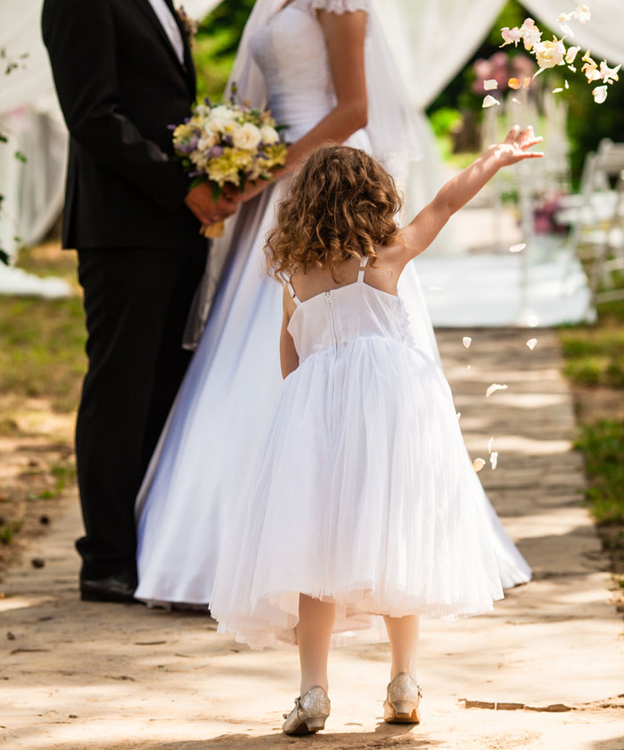 Flower girl throwing petals during outdoor wedding ceremony
