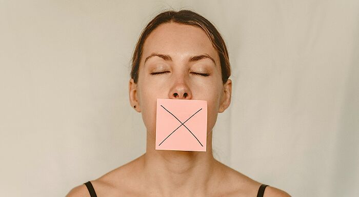 Woman with mouth taped with a cross, mind-bending dilemmas silence concept