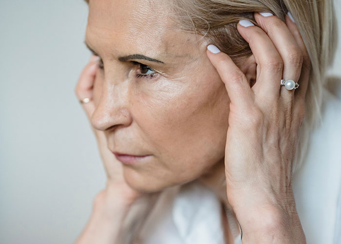 Mature woman with hands to her head, reflecting on moments when kids can't keep contact with parents.