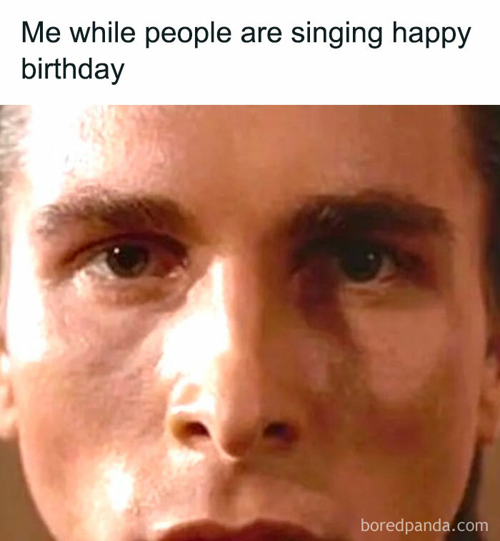 A close-up of a man's face with a neutral expression, captioned Me while people are singing happy birthday, capturing unhinged pics.