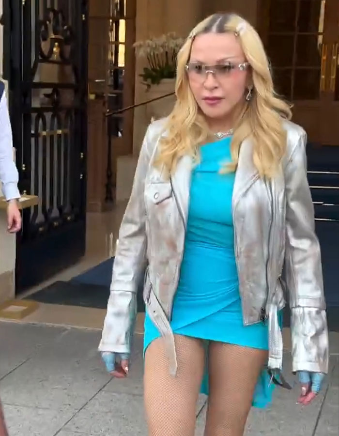 Madonna in a vibrant blue dress and silver jacket after a wardrobe malfunction at Paris Fashion Week.