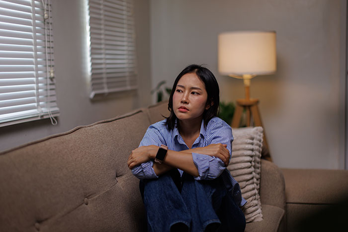 A woman on a couch looking worried, discovering her husband's memory box and stalkerish tendencies. A woman on a couch looking worried, discovering her husband's memory box and stalkerish tendencies.