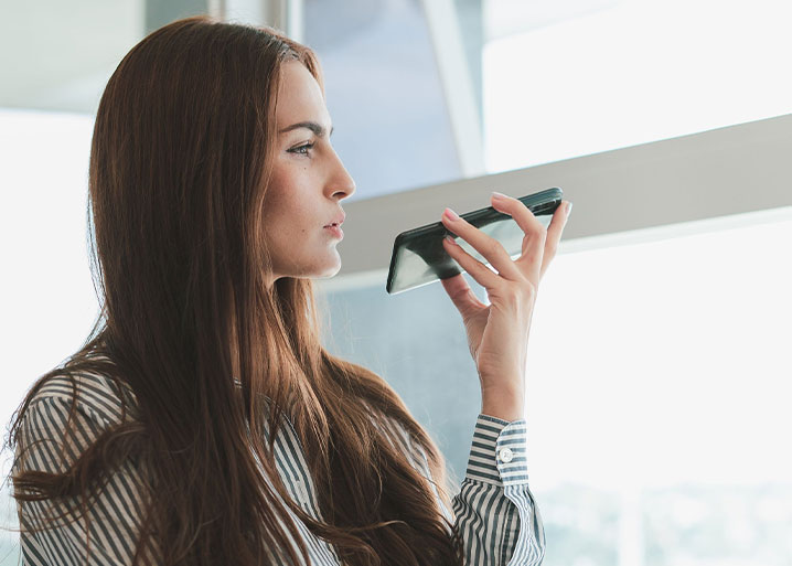 Woman holding smartphone using speakerphone to talk