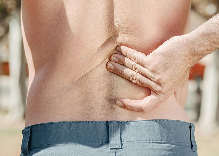 Person holding lower back in pain depicting wild secrets people take straight to their graves