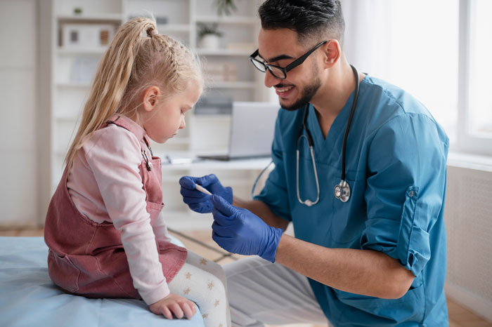 Pediatrician happily examining young girl patient