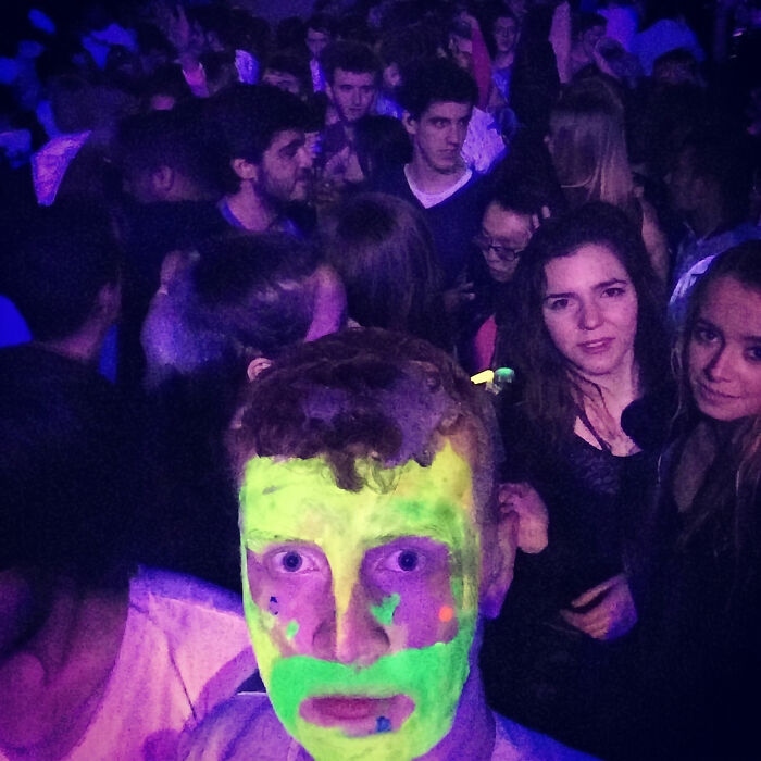 Nightclub photo with man glowing in neon face paint among crowd