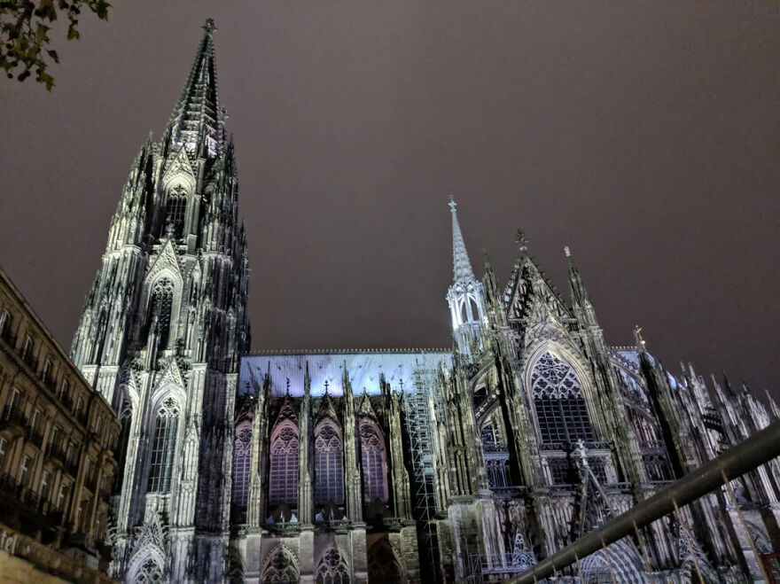 Cologne Cathedral illuminated at night with intricate architecture and towering spires
