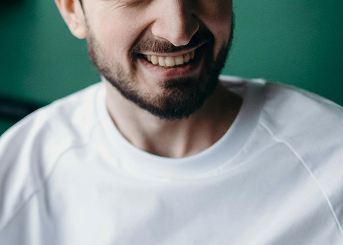 Smiling man with beard wearing white shirt, close-up showing positive emotion
