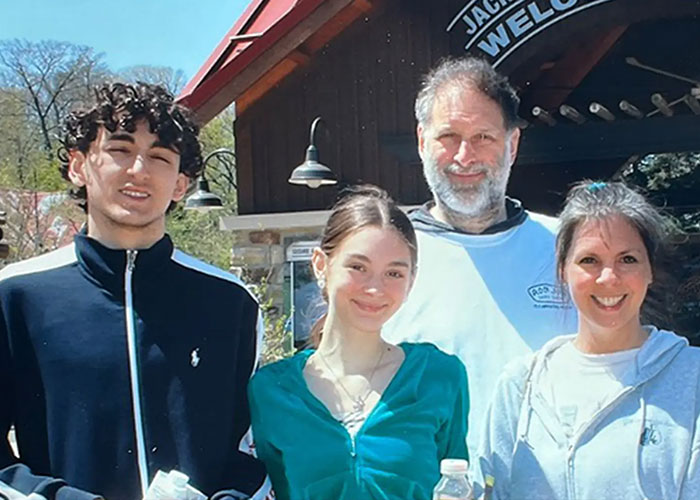 Family of four smiling outdoors in front of a lodge Family of four smiling outdoors in front of a lodge