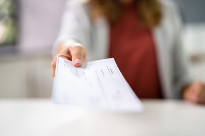 Person handing over a blank check at a desk