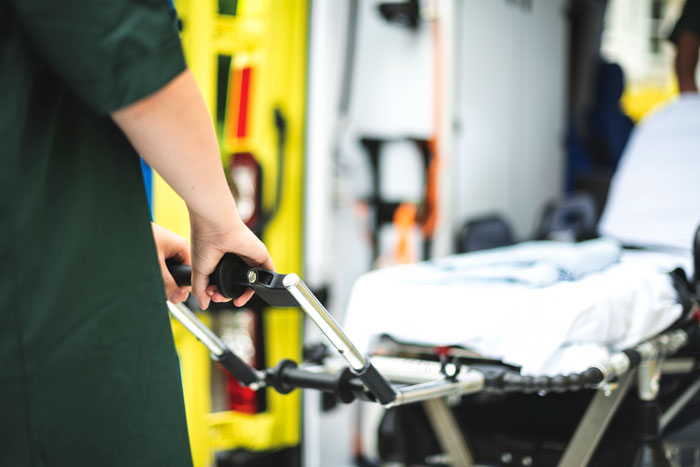 Paramedic pushing empty stretcher into ambulance