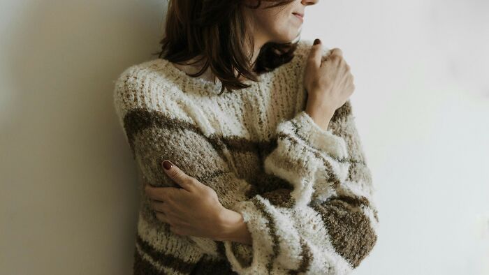 Woman hugging herself wearing a cozy knitted sweater