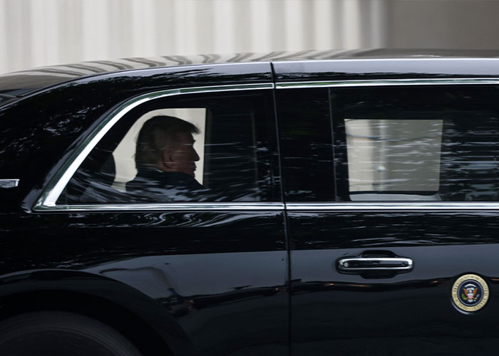 President riding in a black car with presidential seal on door President riding in a black car with presidential seal on door