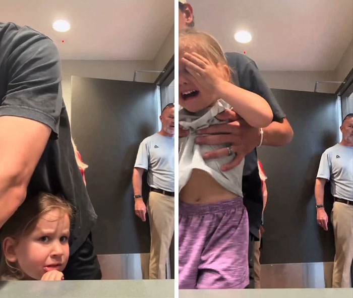Father holding crying daughter in restroom with man watching in background Father holding crying daughter in restroom with man watching in background