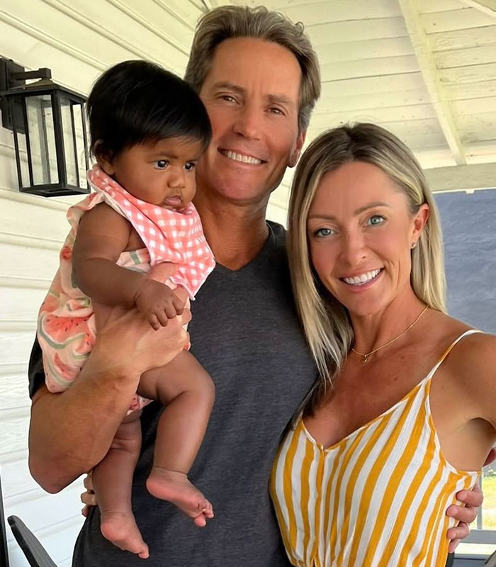 A couple smiling, with the man holding the baby born after an IVF mix-up, who they will keep after striking a deal. A couple smiling, with the man holding the baby born after an IVF mix-up, who they will keep after striking a deal.