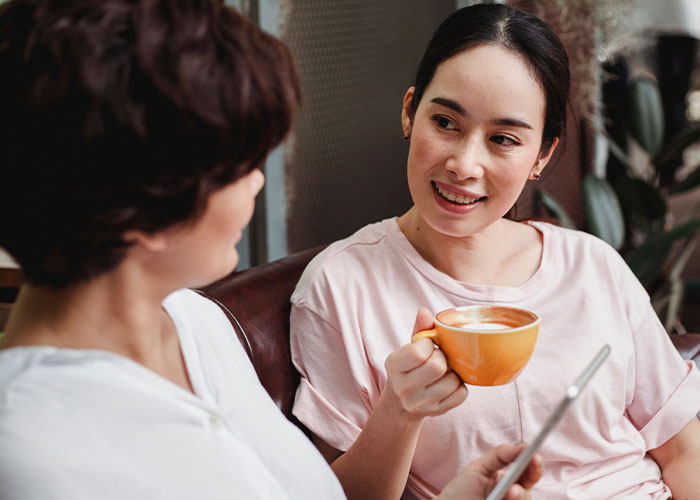 Two women having coffee and conversing, discussing advice that is good but socially not acceptable.