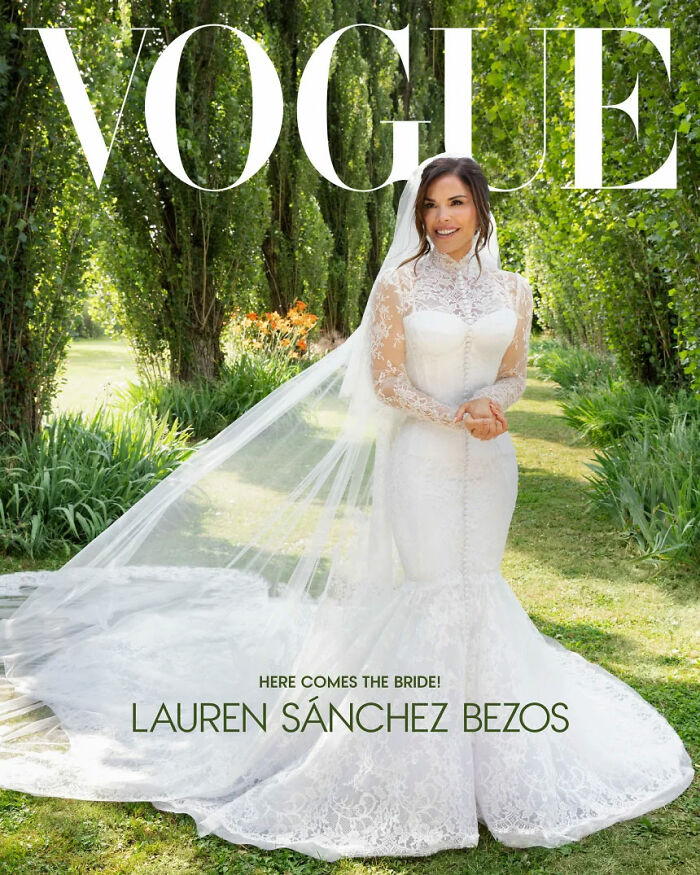 Lauren Sanchez Bezos in a white lace wedding dress with long sleeves and a long veil, smiling outdoors.