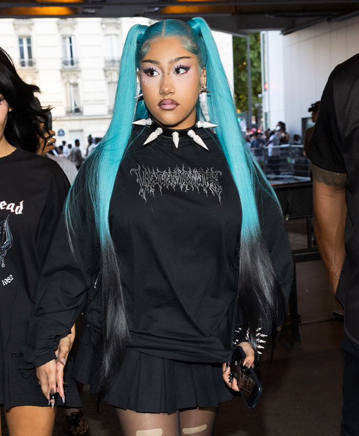 Stylish North wearing black and blue outfit with spiked necklace, capturing attention at a fashion event to protect your kids.