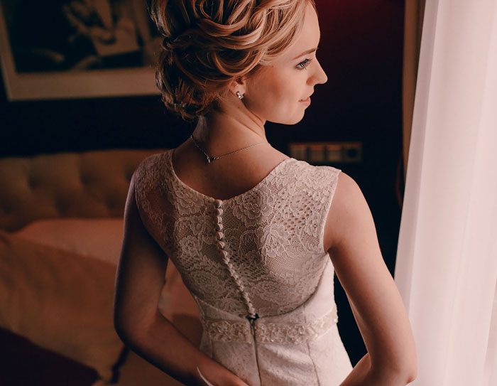 A thoughtful bride in a lace wedding dress, looking out a window. A thoughtful bride in a lace wedding dress, looking out a window.