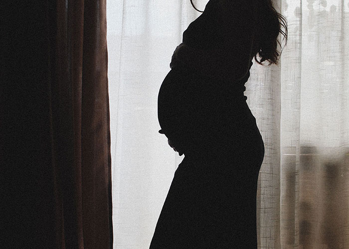 A woman's silhouette, pregnant, standing by a window, as she has suspicions over her husband. A woman's silhouette, pregnant, standing by a window, as she has suspicions over her husband.