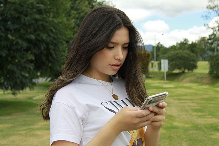 Young woman looking at her phone, contemplating leaving home after refusing to follow a rule.