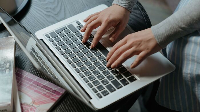 Hands typing on laptop keyboard, mind-bending dilemmas digital interaction