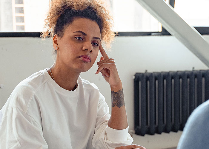 A woman looking displeased, pondering horrible things committed by close friends that broke people's trust.