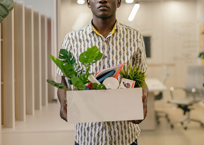 A man leaving an office with a box of personal items, representing that family isn't everything.
