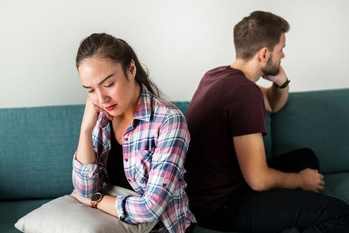 Upset couple sitting back to back on couch, emotional distance in dumping excuses