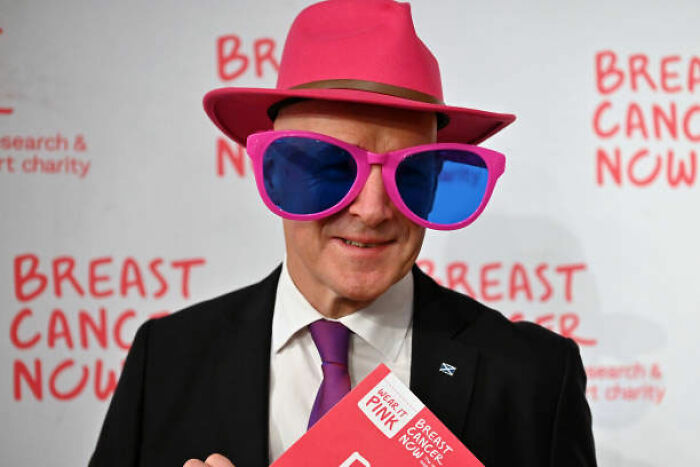 World leader wearing oversized pink sunglasses and hat at breast cancer charity event