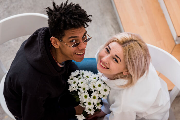 A happy young couple holding a bouquet of flowers, showing people learning things about their friends.