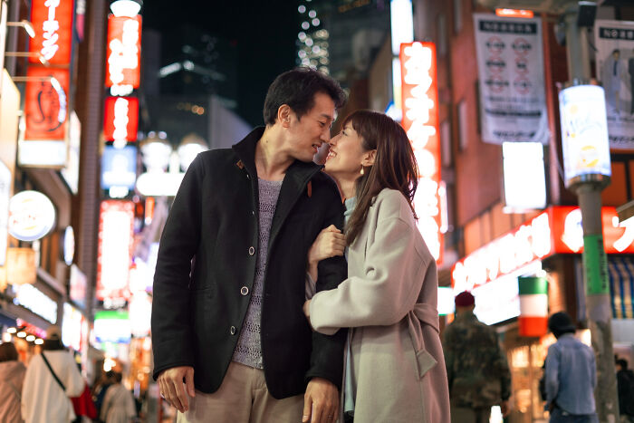 Couple sharing a tender moment in city at night amidst family secrets