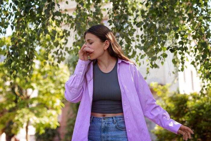 Woman outdoors covering nose due to unpleasant human body odor