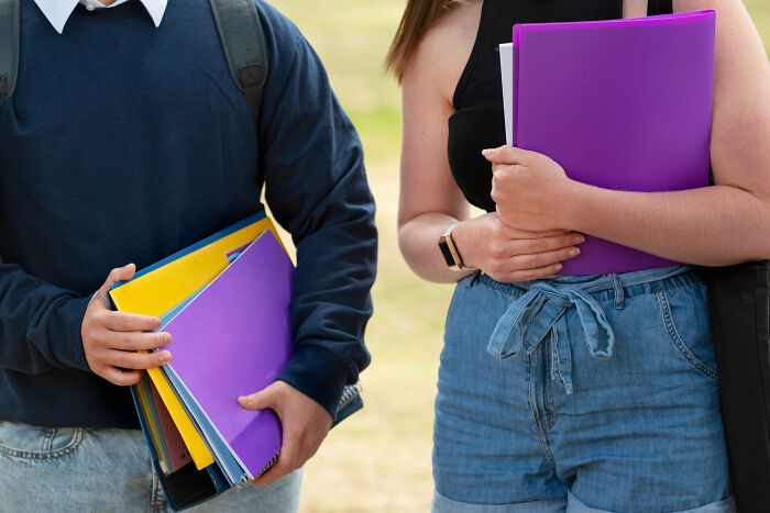 Students holding colorful notebooks outside on campus